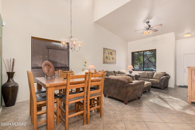 tiled dining space featuring ceiling fan with notable chandelier and a high ceiling