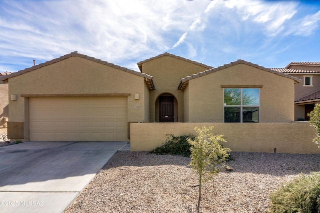 view of front of house featuring a fenced front yard, stucco siding, concrete driveway, a garage, and a tiled roof