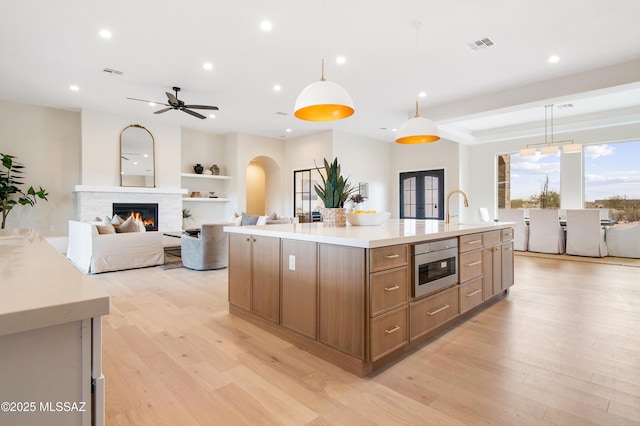 kitchen with french doors, sink, decorative light fixtures, light hardwood / wood-style flooring, and a large island