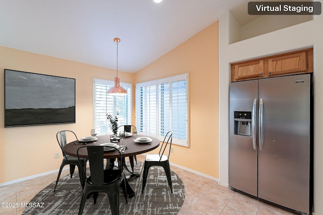 dining room featuring lofted ceiling, light tile patterned flooring, and baseboards