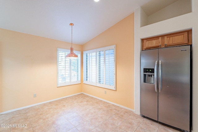 kitchen featuring baseboards, vaulted ceiling, brown cabinetry, stainless steel fridge, and decorative light fixtures