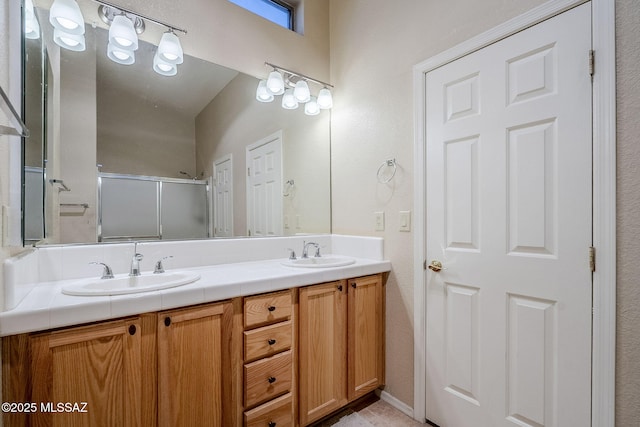 full bath featuring double vanity, an enclosed shower, and a sink