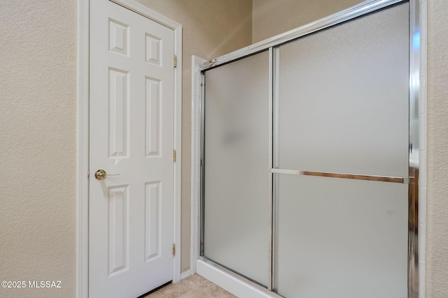 full bathroom featuring a textured wall and a shower with shower door