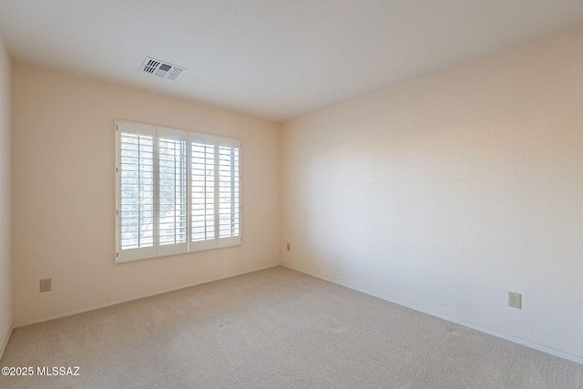 empty room with carpet, visible vents, and baseboards