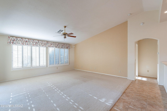 unfurnished room featuring lofted ceiling, visible vents, ceiling fan, and arched walkways