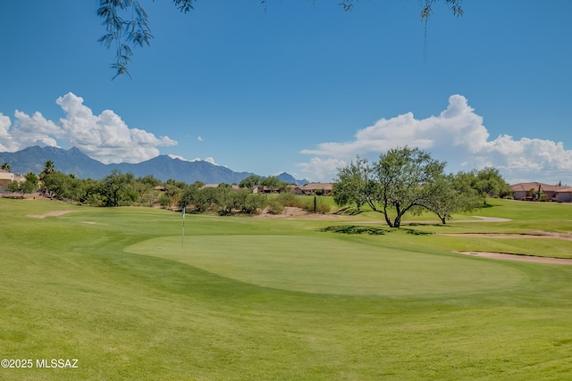 view of home's community featuring view of golf course, a mountain view, and a yard