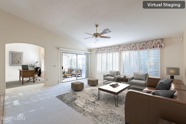 living room featuring lofted ceiling, arched walkways, light colored carpet, a ceiling fan, and visible vents