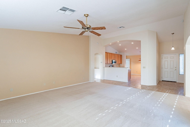 unfurnished living room with high vaulted ceiling, visible vents, arched walkways, and light colored carpet