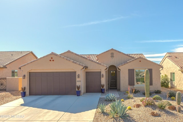 mediterranean / spanish house with driveway, a tiled roof, an attached garage, and stucco siding