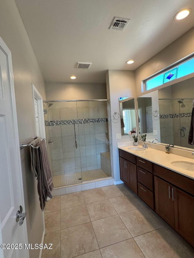 bathroom with double vanity, a sink, visible vents, and a shower stall