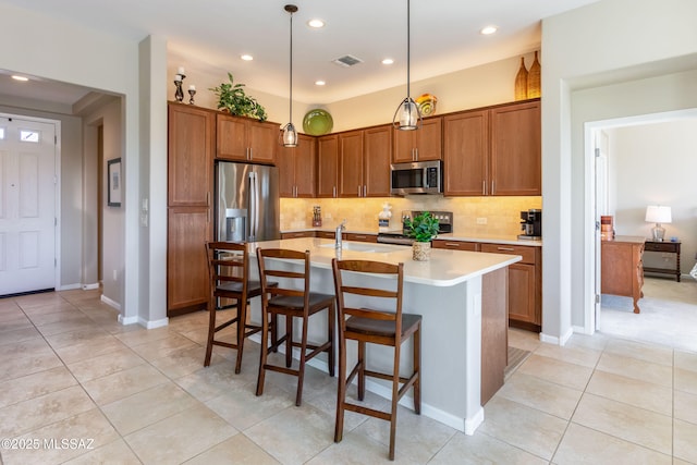 kitchen featuring brown cabinetry, tasteful backsplash, stainless steel appliances, and light countertops