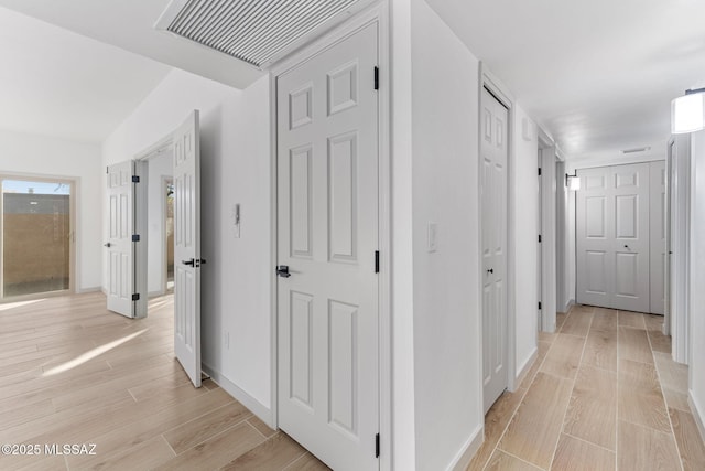 hall with wood tiled floor, visible vents, and baseboards