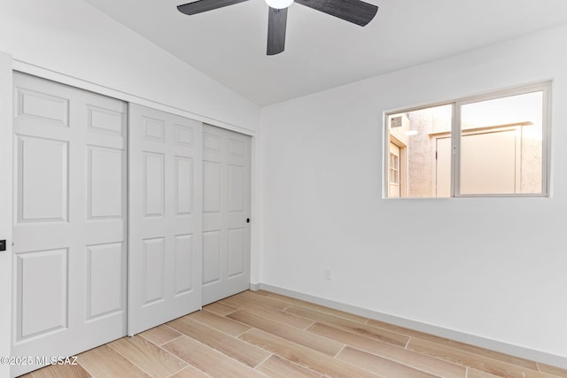 unfurnished bedroom with ceiling fan, lofted ceiling, baseboards, a closet, and wood tiled floor