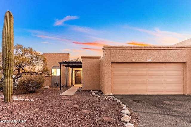 adobe home with driveway, an attached garage, and stucco siding