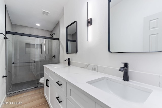 bathroom featuring double vanity, a stall shower, visible vents, and a sink