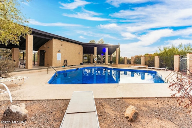 community pool with a patio and fence