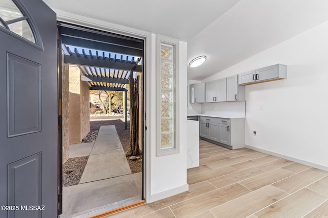 interior space featuring wood tiled floor, lofted ceiling, and baseboards