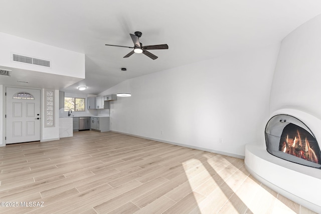 unfurnished living room with a lit fireplace, visible vents, light wood-style flooring, and baseboards