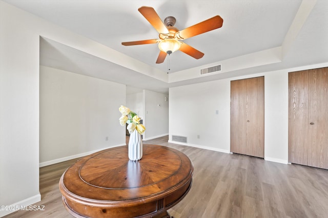 sitting room with hardwood / wood-style floors, a tray ceiling, and ceiling fan