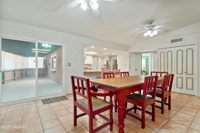 dining room with light tile patterned floors, visible vents, ceiling fan, and brick wall