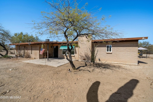 rear view of property featuring brick siding and a patio area