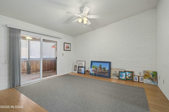 living room featuring brick wall, ceiling fan, and wood finished floors