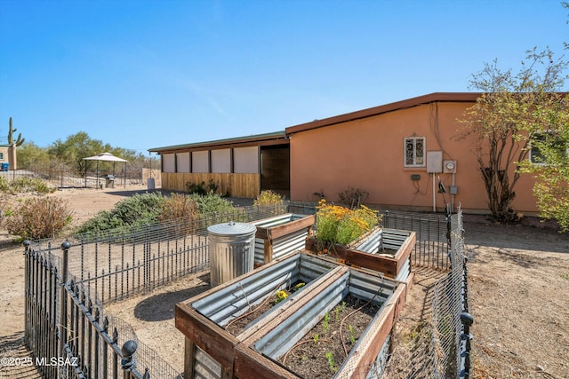 back of property featuring a garden, stucco siding, and fence