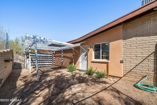 view of side of property featuring a gate, stucco siding, a patio, and fence