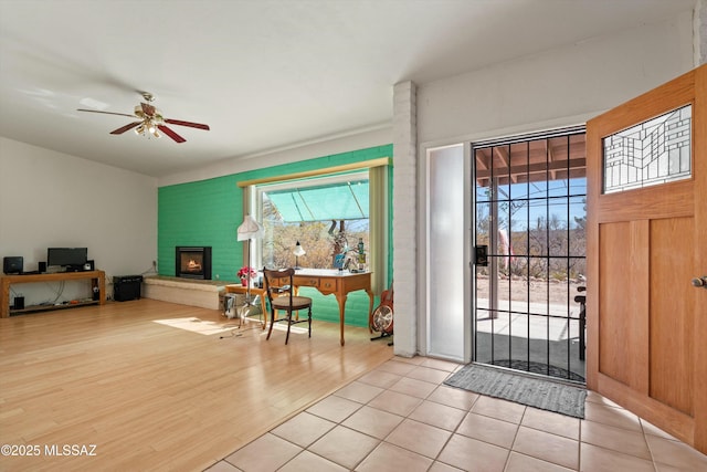 foyer entrance featuring a fireplace, ceiling fan, and wood finished floors