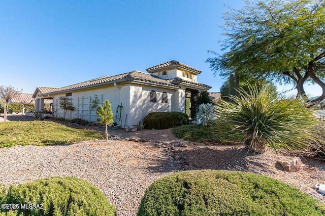 view of side of property with a tiled roof and stucco siding