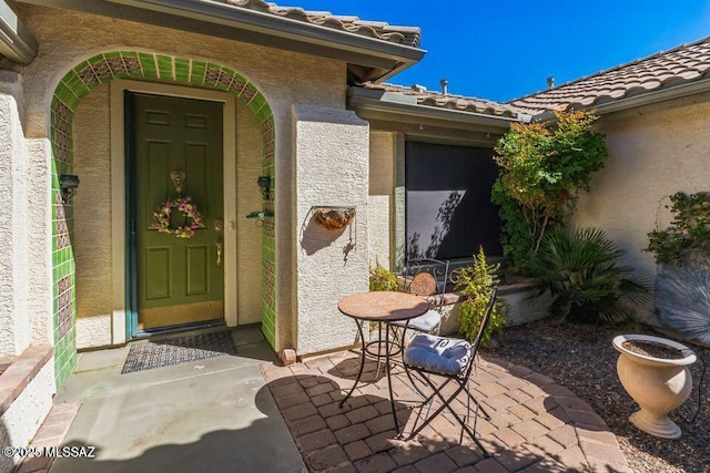 doorway to property featuring a patio area, a tile roof, and stucco siding