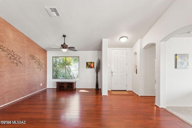 interior space featuring arched walkways, wood finished floors, visible vents, a ceiling fan, and vaulted ceiling