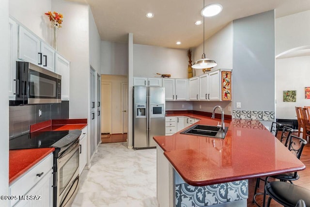 kitchen with dark countertops, a breakfast bar, a peninsula, stainless steel appliances, and a sink