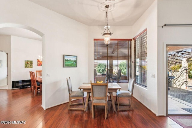 dining room featuring arched walkways, dark wood finished floors, baseboards, and an inviting chandelier