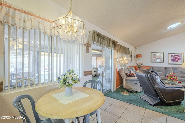 dining room with lofted ceiling, tile patterned flooring, a textured ceiling, and an inviting chandelier