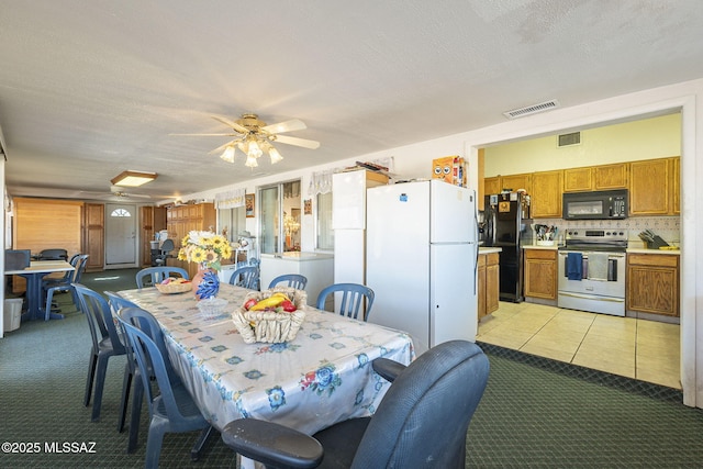 dining space with a textured ceiling, light colored carpet, and ceiling fan