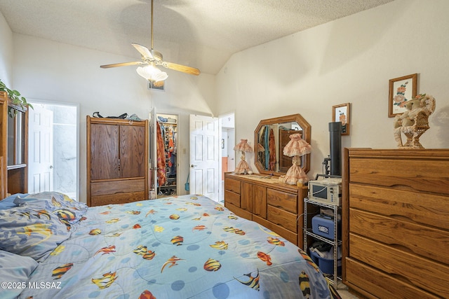 bedroom featuring ceiling fan, high vaulted ceiling, a textured ceiling, a walk in closet, and a closet