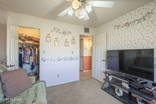 interior space featuring ceiling fan, a closet, a textured ceiling, and a walk in closet