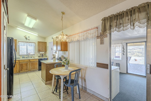 kitchen featuring lofted ceiling, sink, light tile patterned floors, pendant lighting, and black appliances