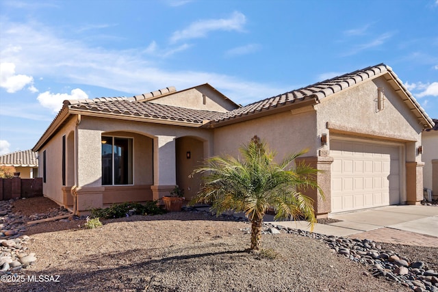 view of front facade with concrete driveway, a tile roof, an attached garage, and stucco siding