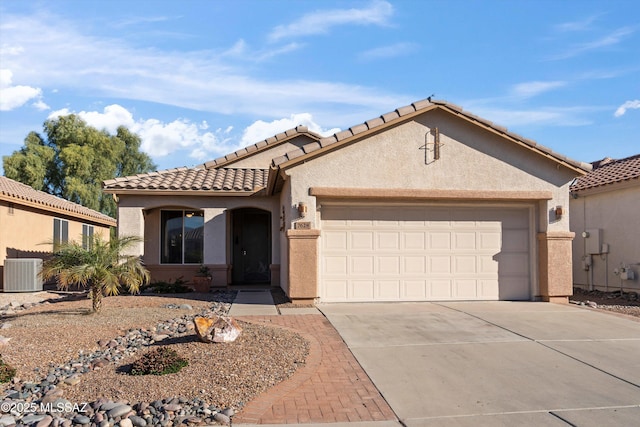 mediterranean / spanish house with stucco siding, central air condition unit, an attached garage, driveway, and a tiled roof