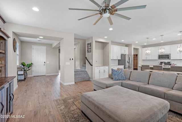 living area with ceiling fan, recessed lighting, baseboards, light wood-style floors, and stairway