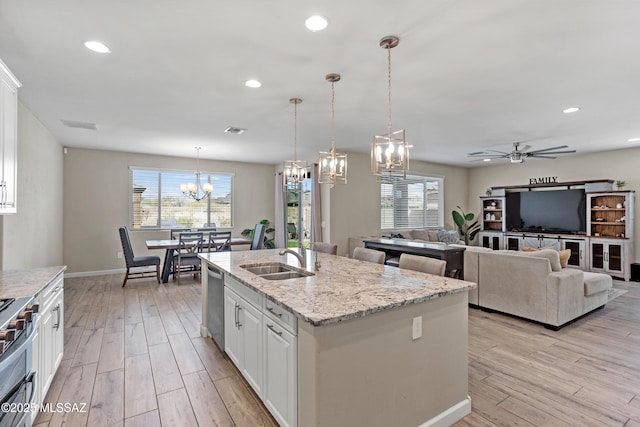 kitchen with a kitchen island with sink, stainless steel appliances, a sink, and light wood-style flooring