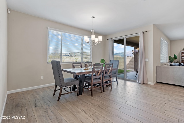 dining room with light wood-type flooring, an inviting chandelier, and baseboards