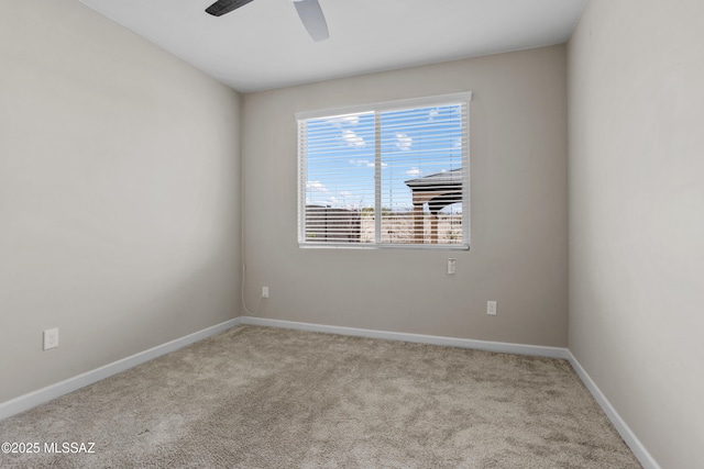 carpeted spare room featuring ceiling fan and baseboards