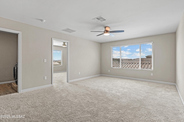 empty room with carpet floors, visible vents, and baseboards