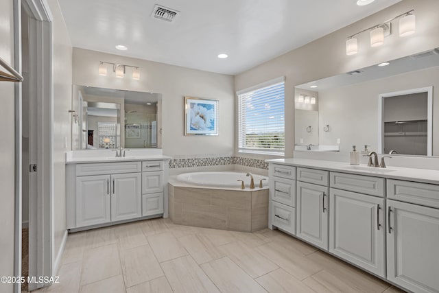 full bath featuring a garden tub, a stall shower, a sink, and visible vents