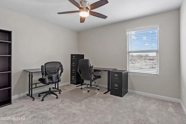 carpeted office space with ceiling fan and baseboards