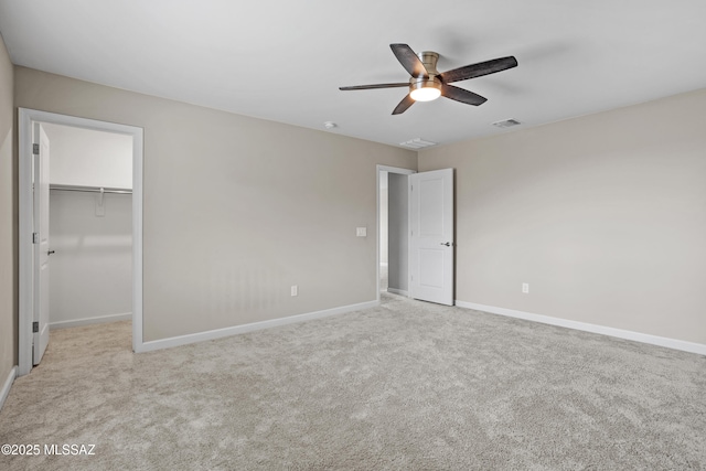 unfurnished bedroom with baseboards, visible vents, a ceiling fan, light colored carpet, and a spacious closet