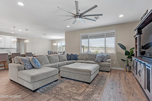 living area featuring recessed lighting, baseboards, visible vents, wood finished floors, and ceiling fan with notable chandelier